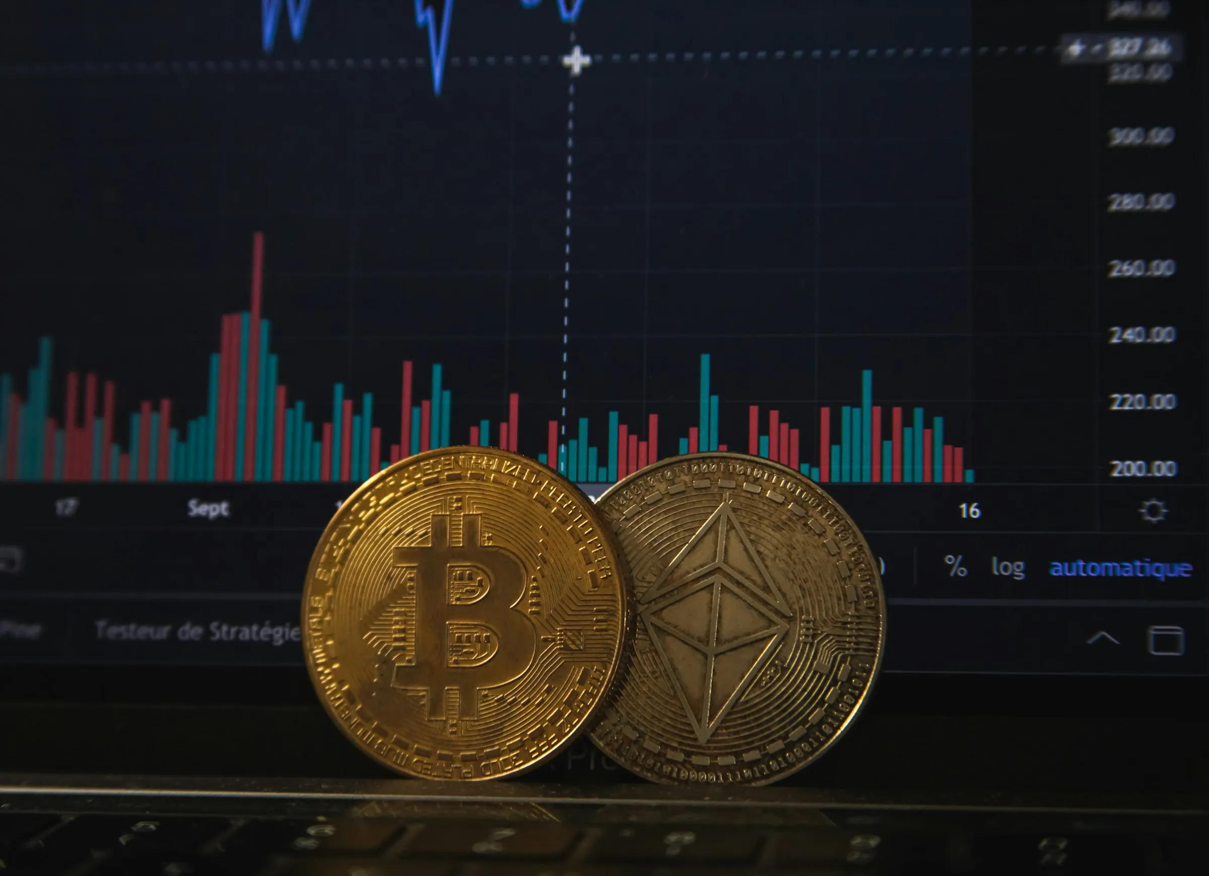 Bitcoin un Ethereum monētas uz klēpjdatora pie tirdzniecības grafika